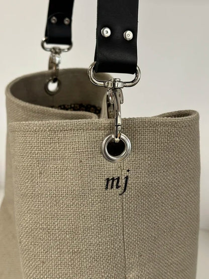 L'anse en cuir noir amovible du sac hobo en lin beige, avec personnalisation extérieure