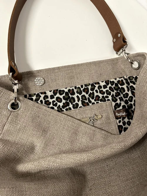 La poche intérieure zippée du sac Hobo en lin beige et léopard avec anse en cuir marron