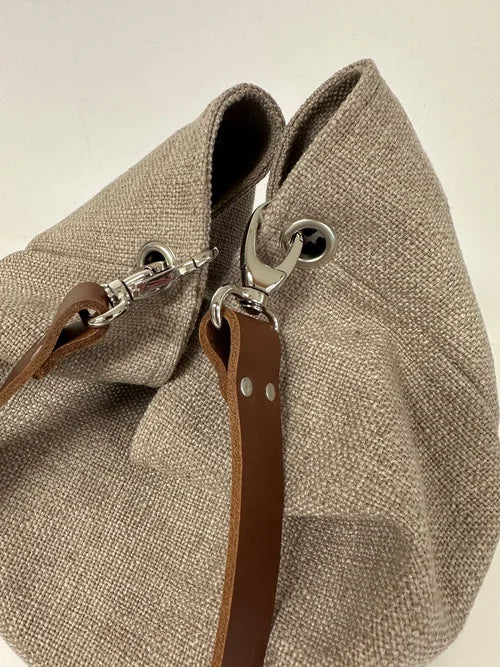 Les accroches de l'anse en cuir du sac Hobo en lin beige et léopard avec anse en cuir marron