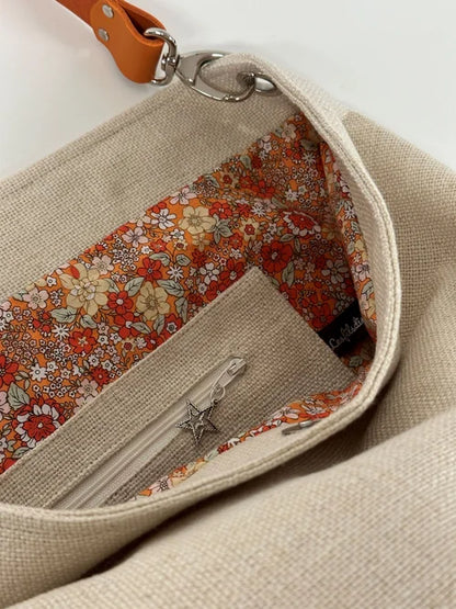 La poche zippée intérieure du sac Hobo en lin ivoire et anse en cuir orange