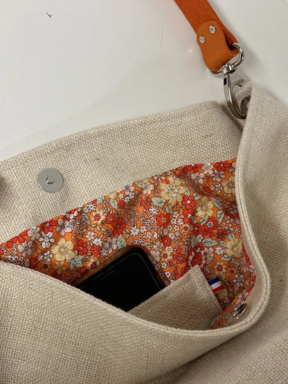 La poche plaquée intérieure du sac Hobo en lin ivoire et anse en cuir orange