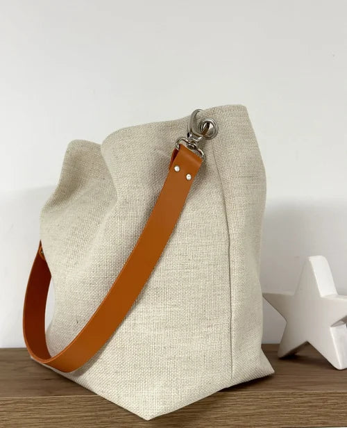 Vue d'ensemble du sac Hobo en lin ivoire et son anse en cuir orange