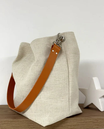Vue d'ensemble du sac Hobo en lin ivoire et son anse en cuir orange