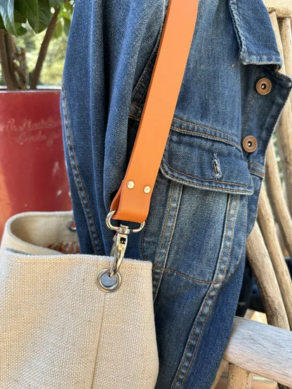 Vue détaillée de l'anse en cuir orange du sac Hobo en lin ivoire.