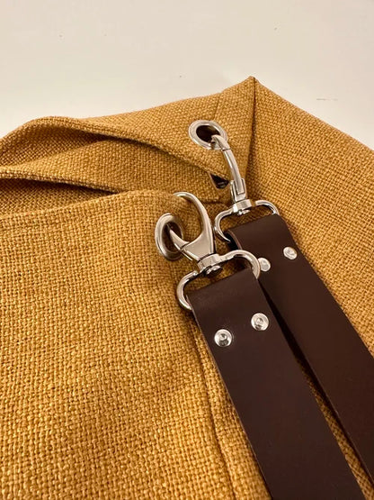 les accroches de l'anse en cuir sur le sac Hobo en lin moutarde et son anse en cuir marron