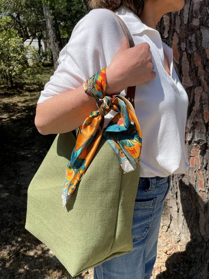 le sac hobo en lin vert kaki et son anse en cuir marron amovible, porté à l'épaule