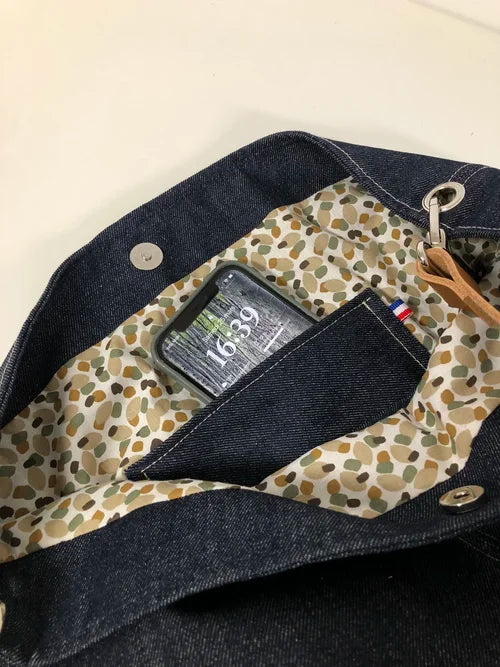 La poche intérieure plaquée du sac hobo en toile denim brut et son anse en cuir fauve