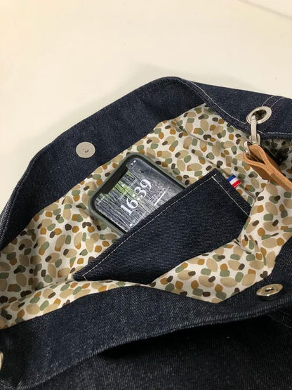 La poche intérieure plaquée du sac hobo en toile denim brut et son anse en cuir fauve