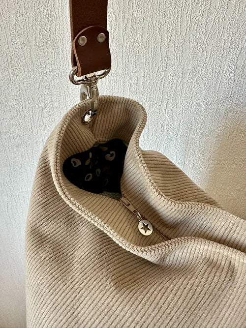 Le sac hobo en velours cotelé beige et son anse en cuir marron, avec fermeture éclair