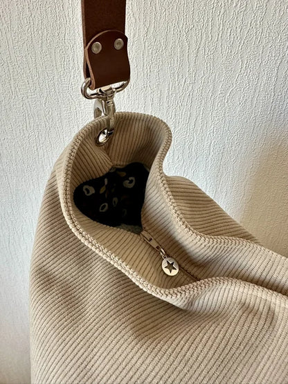 Le sac hobo en velours cotelé beige et son anse en cuir marron, avec fermeture éclair