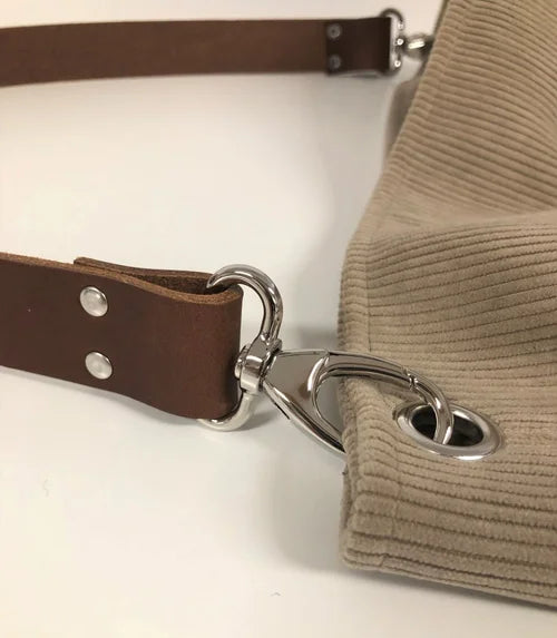 Vue détaillée des accroches de l'anse en cuir marron du sac hobo en velours cotelé beige 