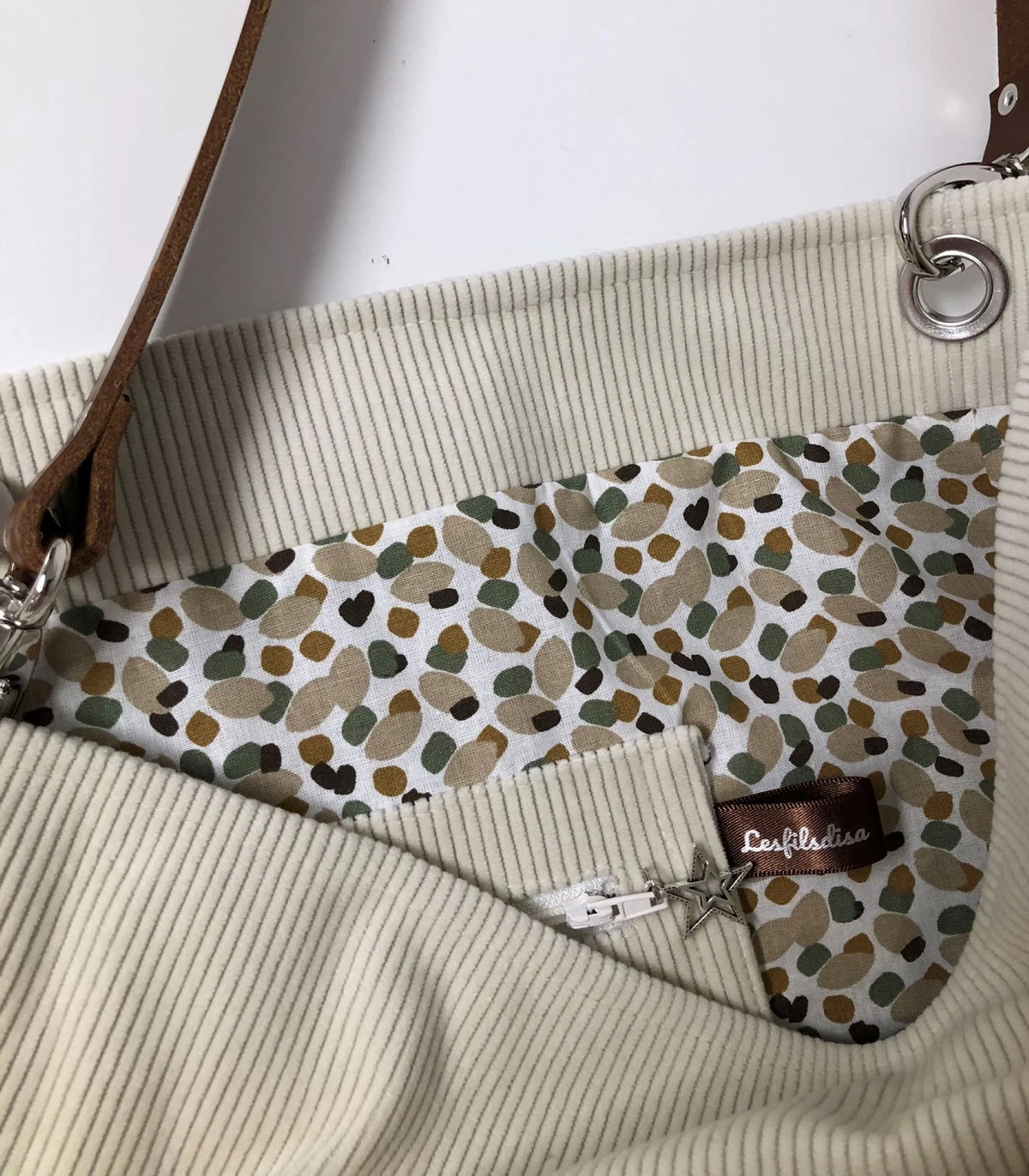 La poche intérieure zippée du sac hobo en velours cotelé ivoire et son anse en cuir .