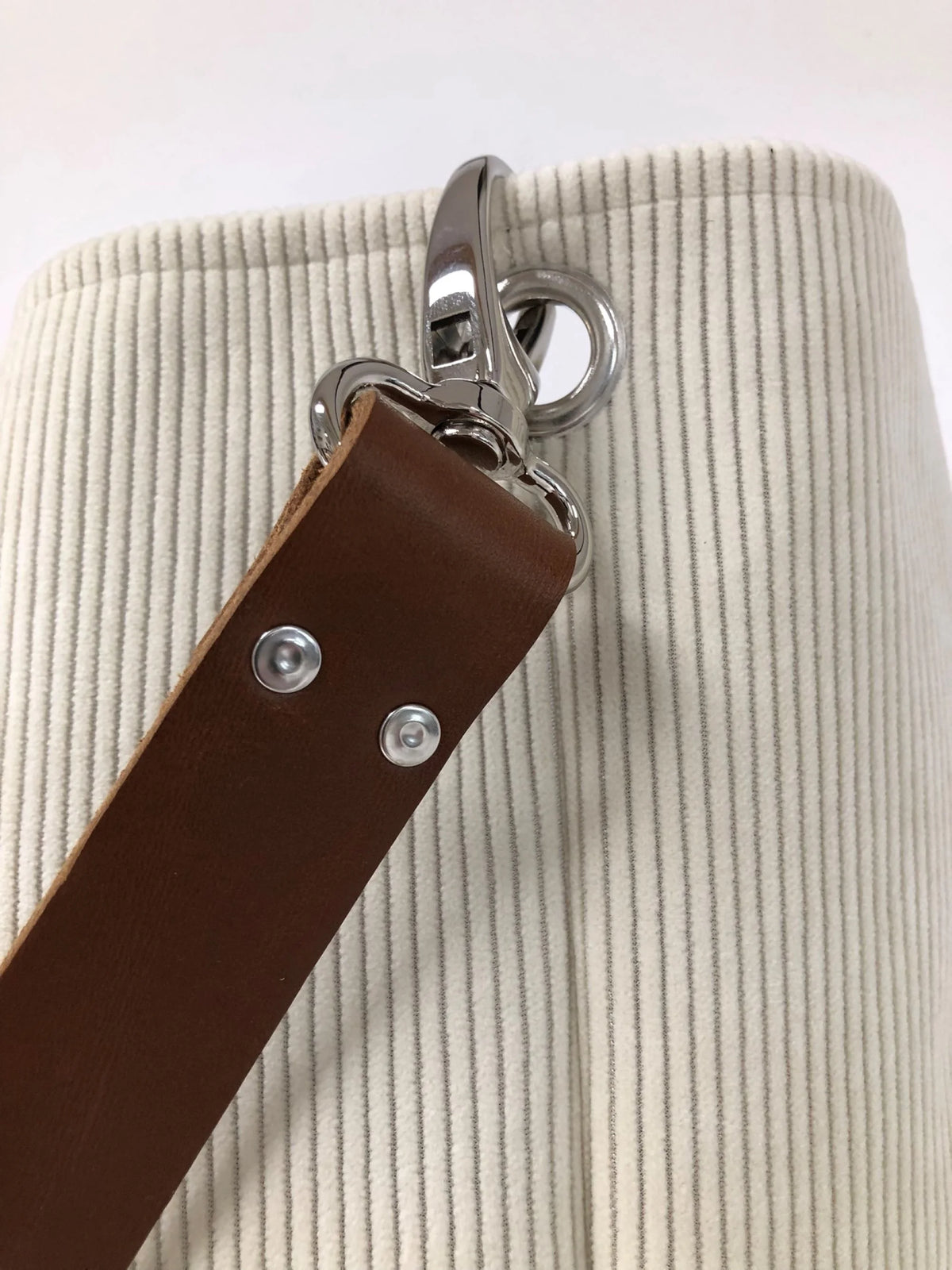 Vue détaillée du sac hobo en velours cotelé ivoire et son anse en cuir marron.