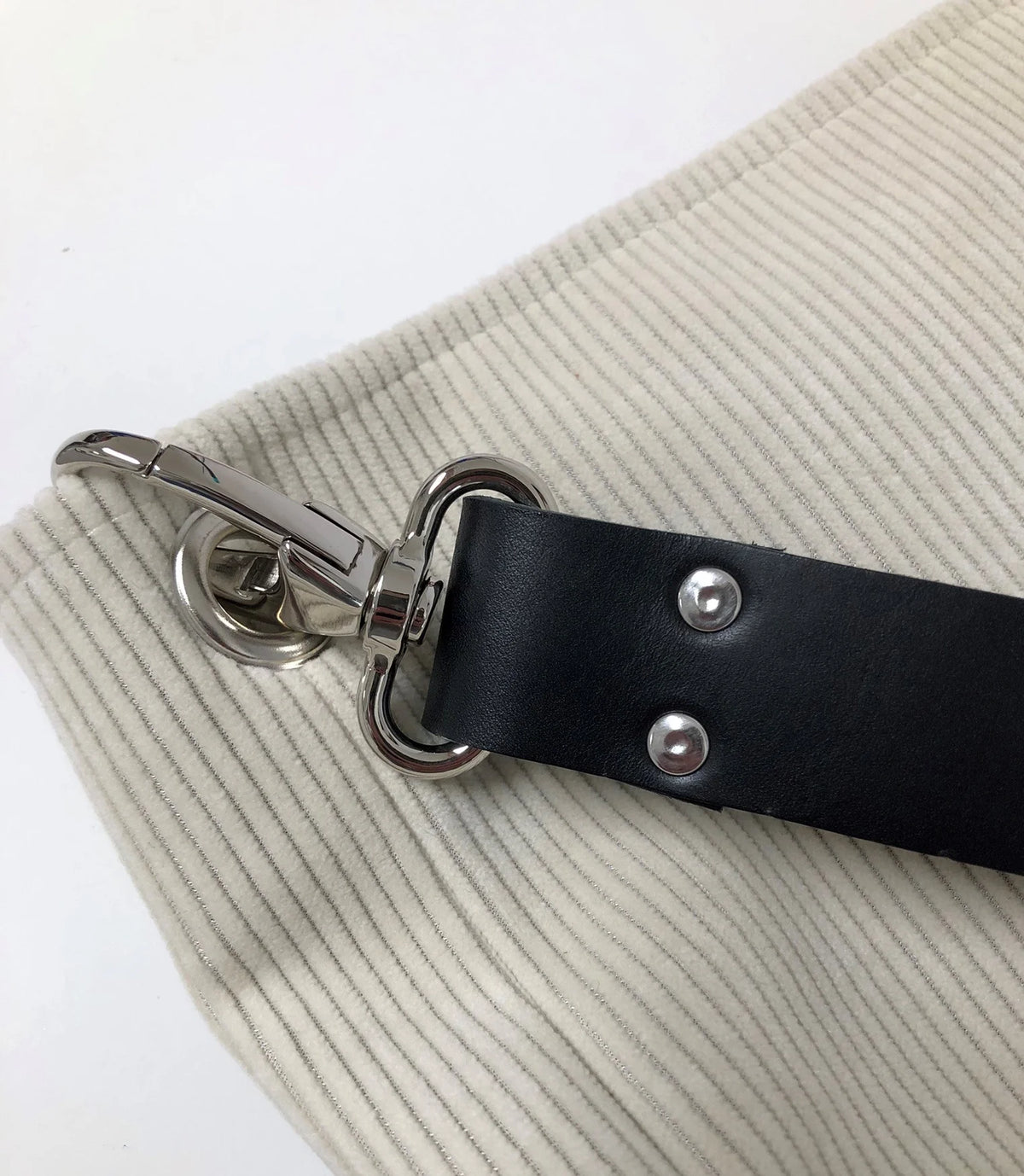 Vue détaillée du sac hobo en velours cotelé ivoire et son anse en cuir noir.