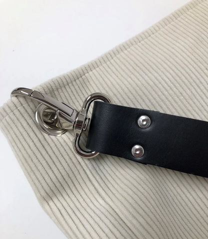 Vue détaillée du sac hobo en velours cotelé ivoire et son anse en cuir noir.