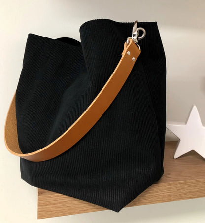 Le sac hobo en velours cotelé noir et son anse en cuir fauve.