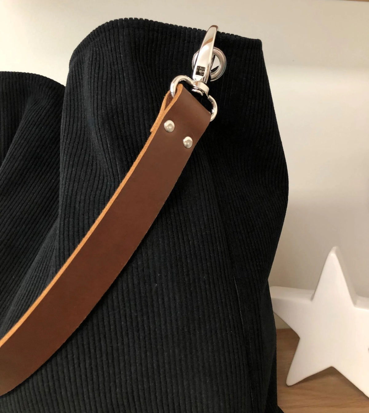 L'anse en cuir marron du sac hobo en velours cotelé noir .
