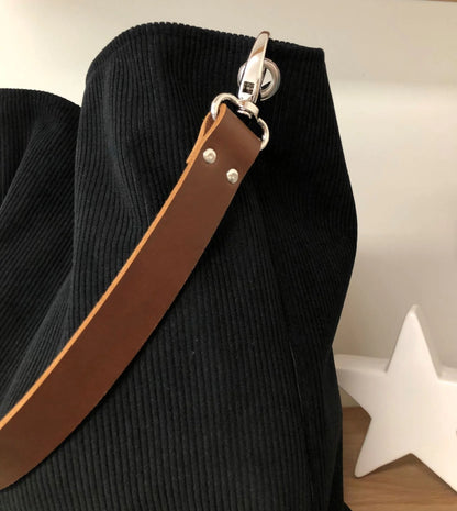 L'anse en cuir marron du sac hobo en velours cotelé noir .
