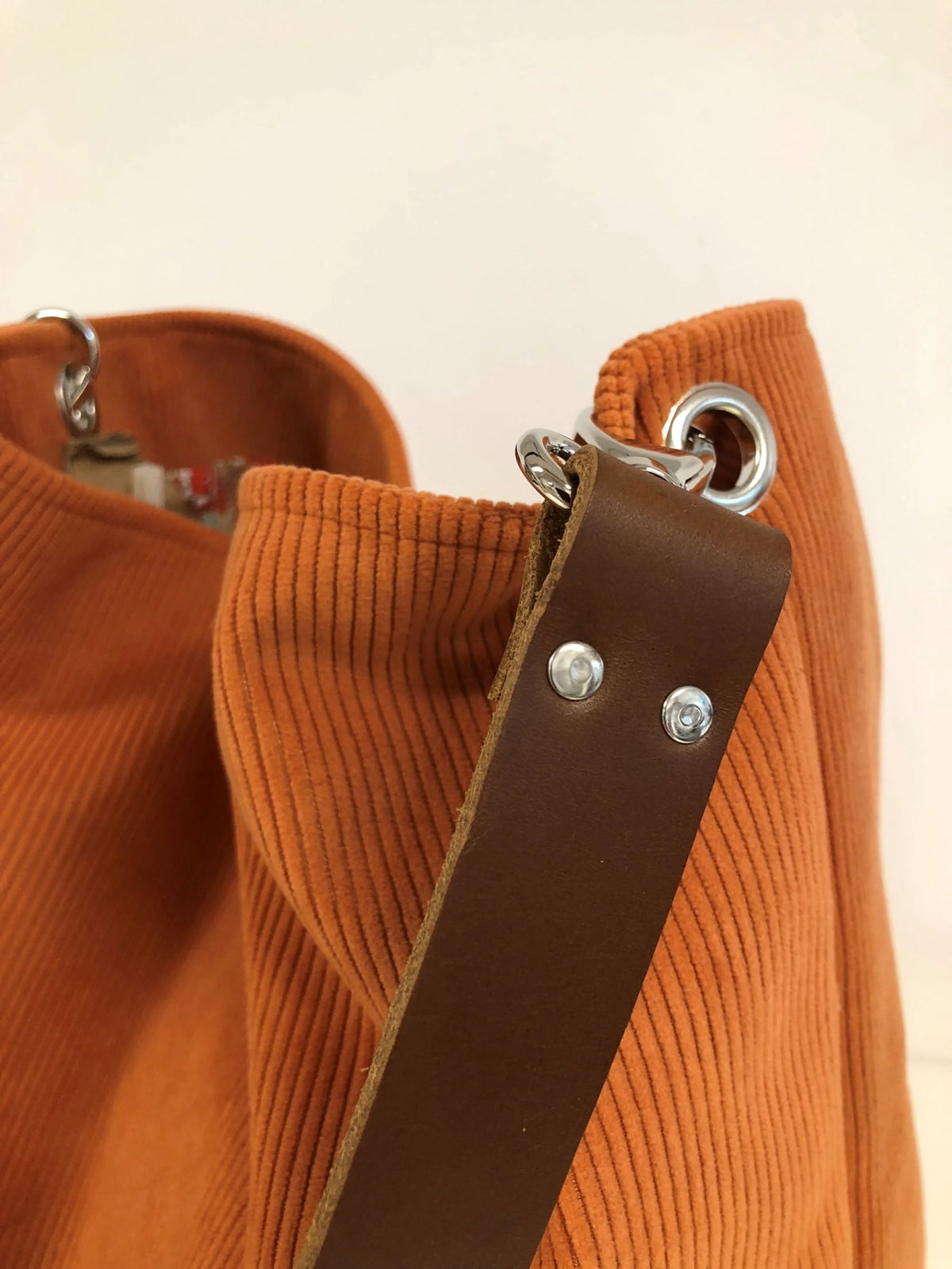 L'anse en cuir marron amovible du sac hobo en velours cotelé orange.