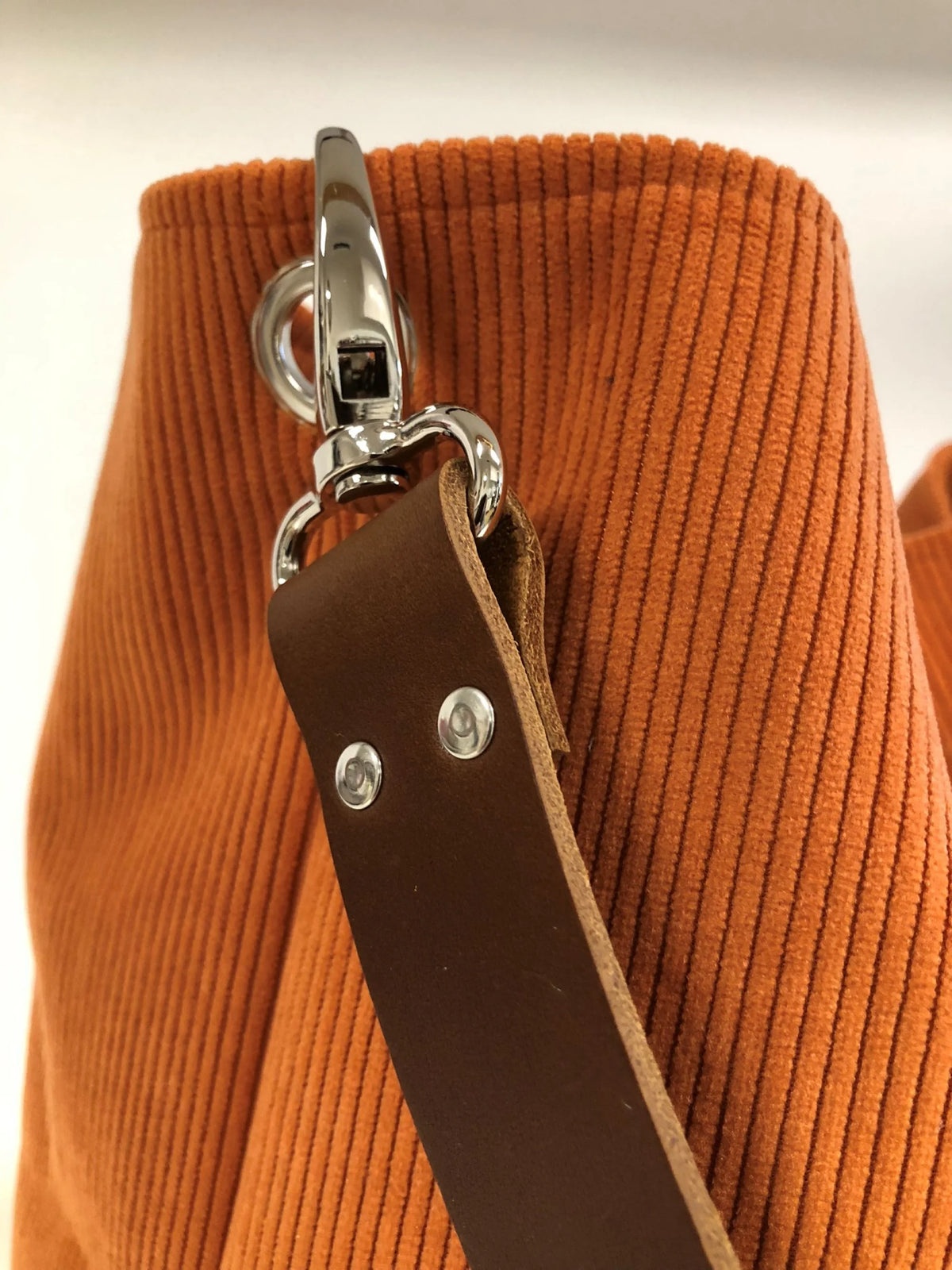 L'anse en cuir amovible du sac hobo en velours cotelé orange.