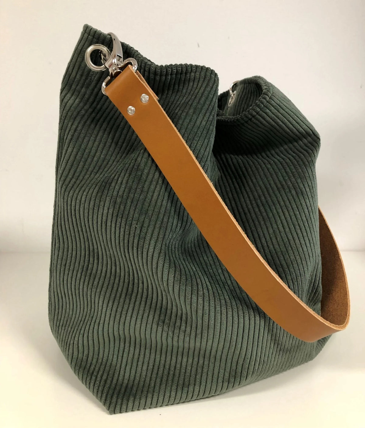 Le sac hobo en velours cotelé vert kaki et anse en cuir fauve.