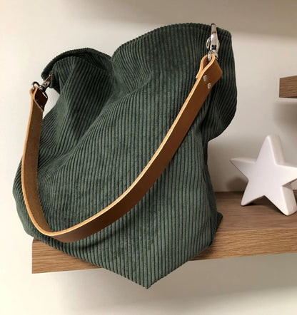 Le sac hobo en velours cotelé vert kaki et anse en cuir fauve.