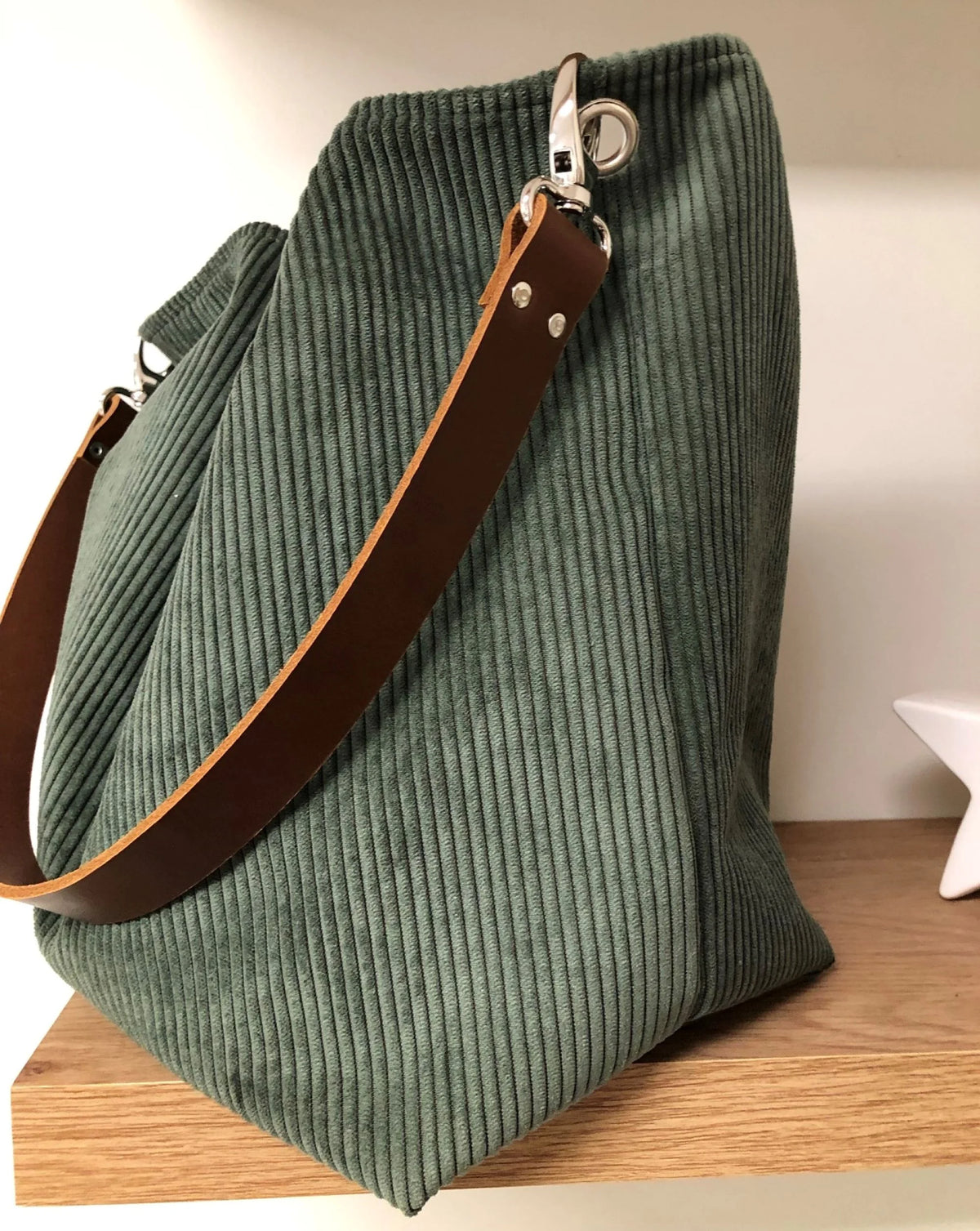 Le sac hobo en velours cotelé vert kaki et anse en cuir marron.