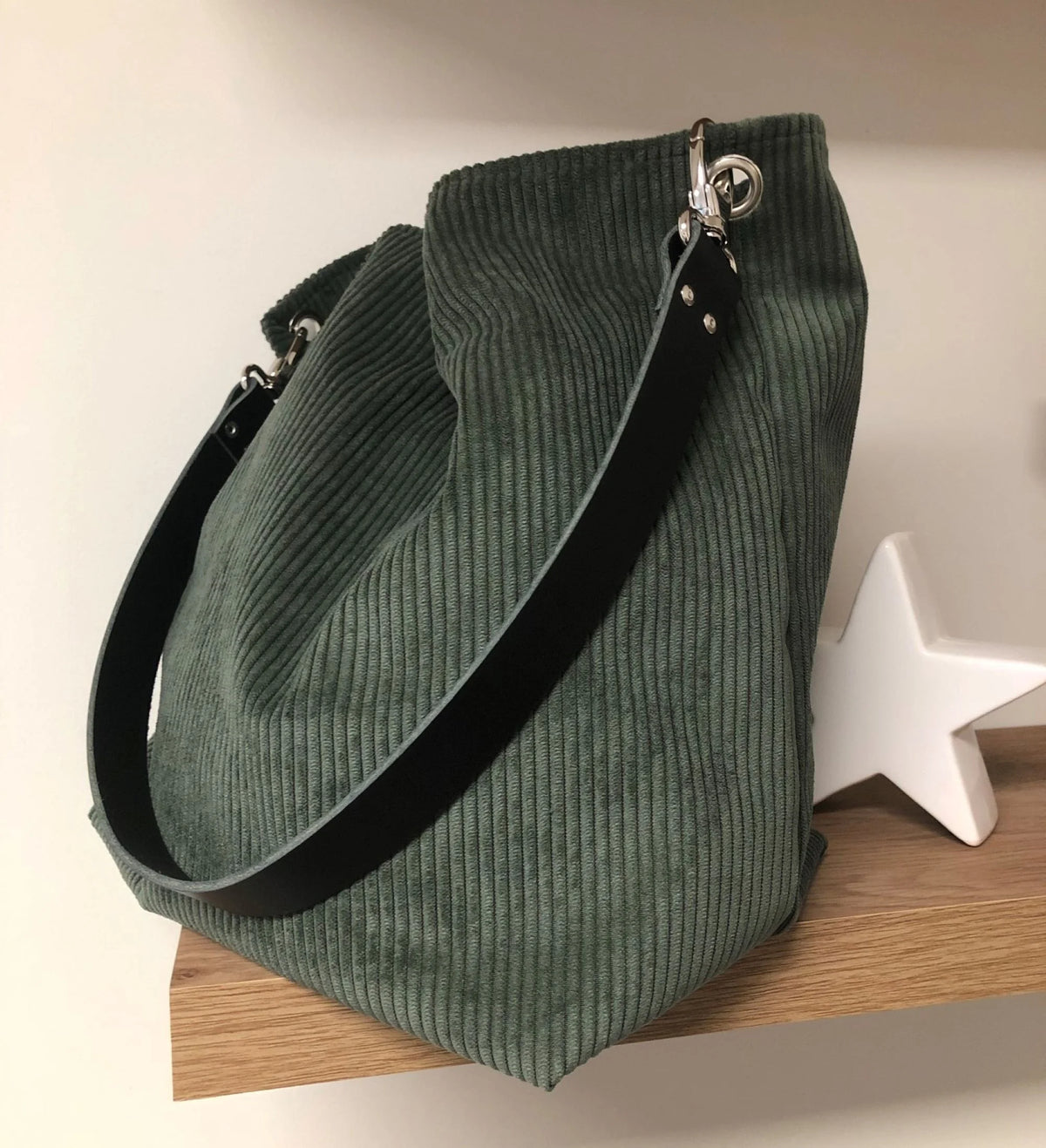 Le sac hobo en velours cotelé vert kaki et anse en cuir noir.