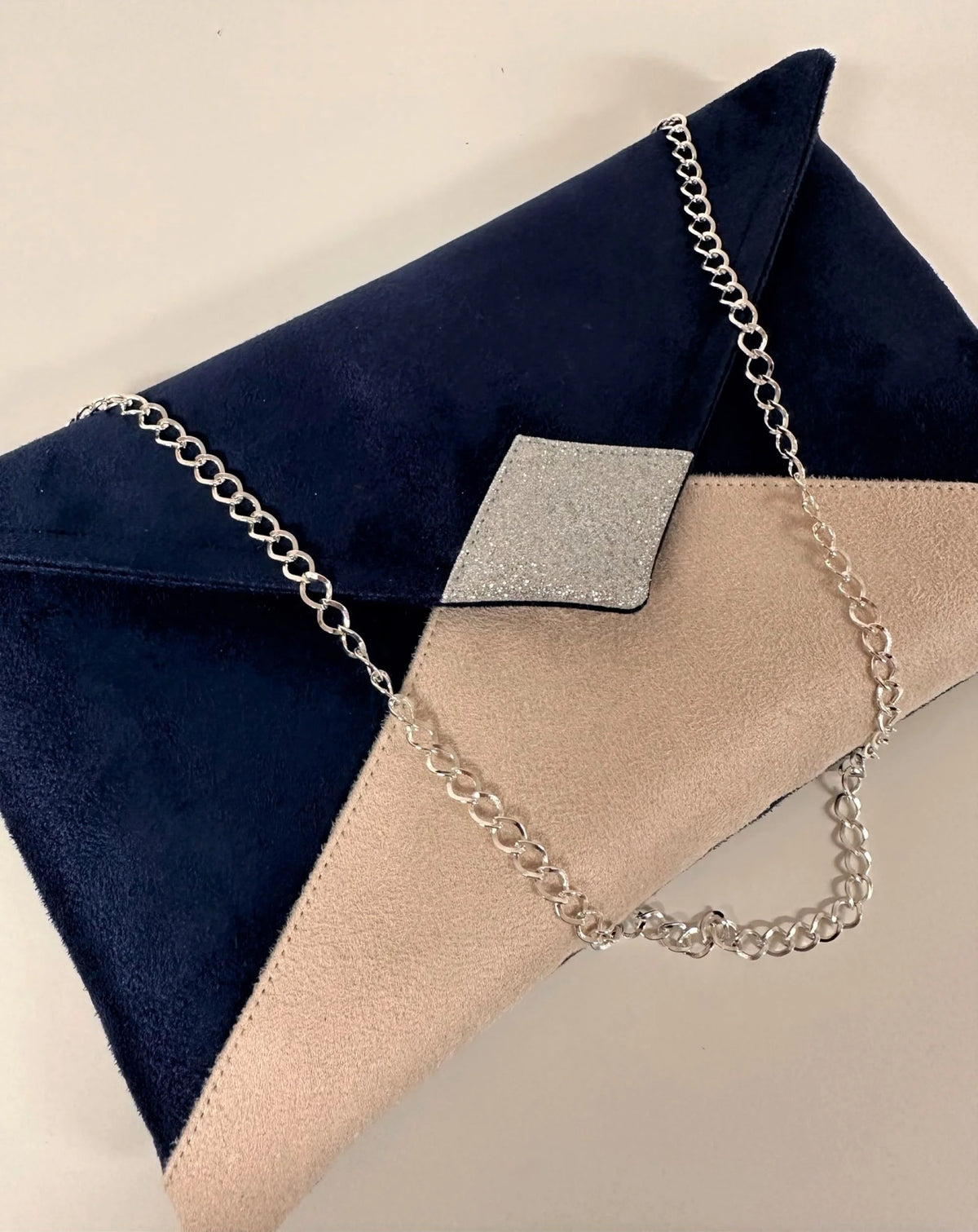 Vue de face avant du sac pochette Isa bleu marine et beige nude à paillettes argentées avec sa chainette amovible.