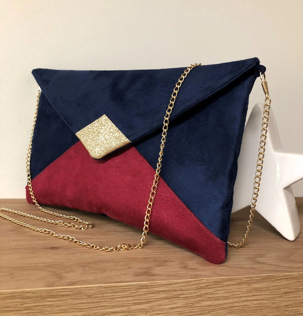 Le  sac pochette Isa bleu marine et fuchsia à paillettes dorées, avec chainette amovible, face avant.