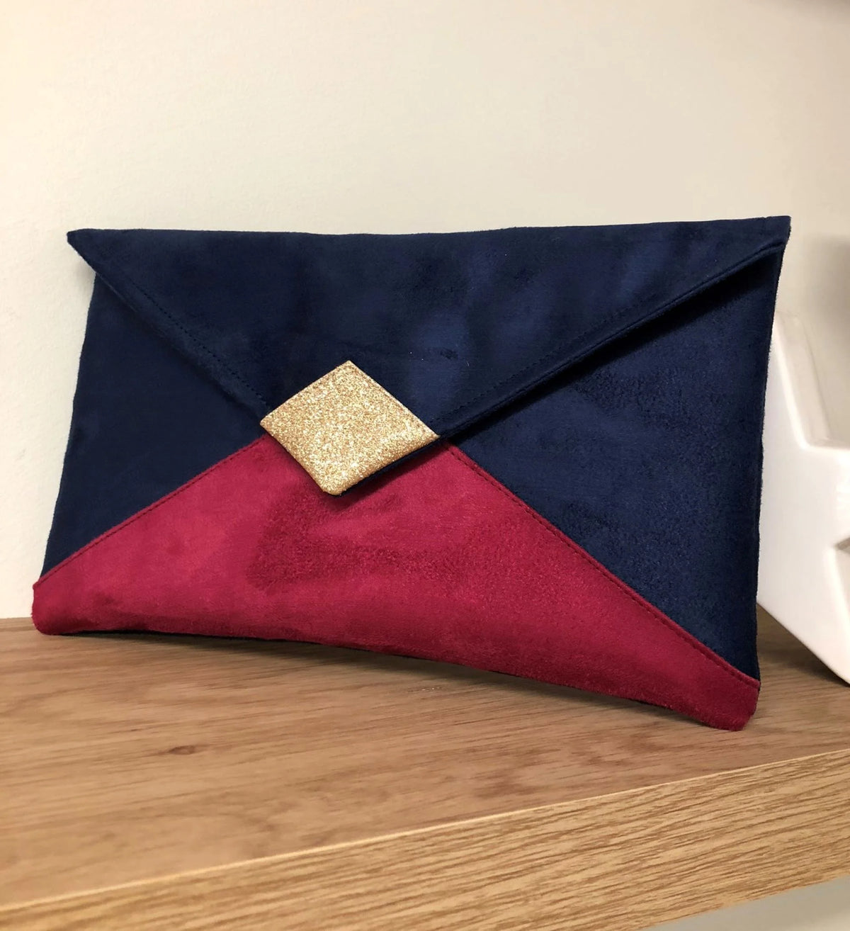Le  sac pochette Isa bleu marine et fuchsia à paillettes dorées, sans chainette amovible.
