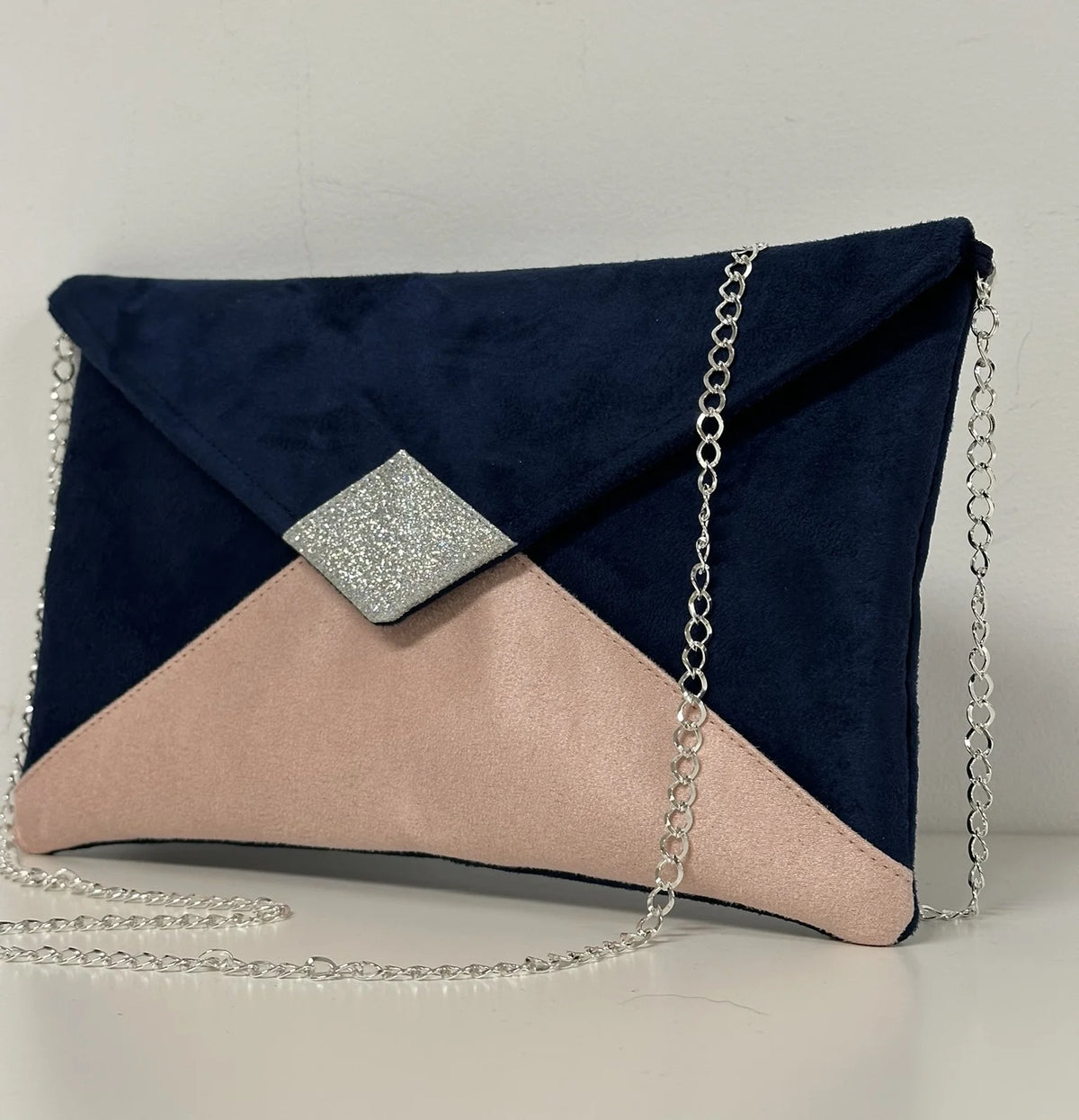 Le sac pochette Isa bleu marine et rose poudré à paillettes argentées, avec chainette amovible.