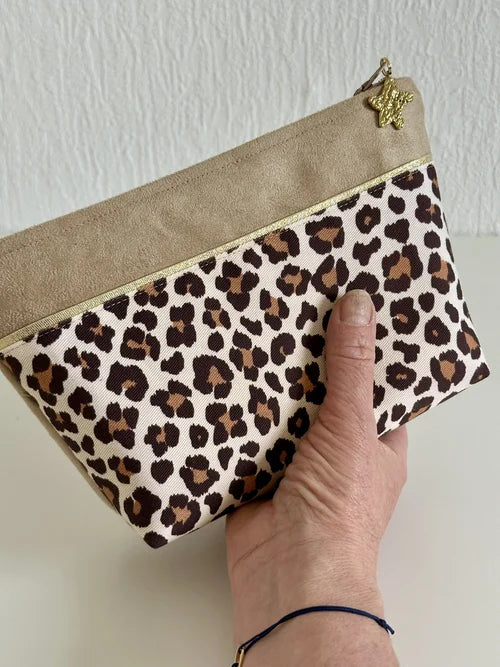 La trousse à maquillage léopard tenue en main.