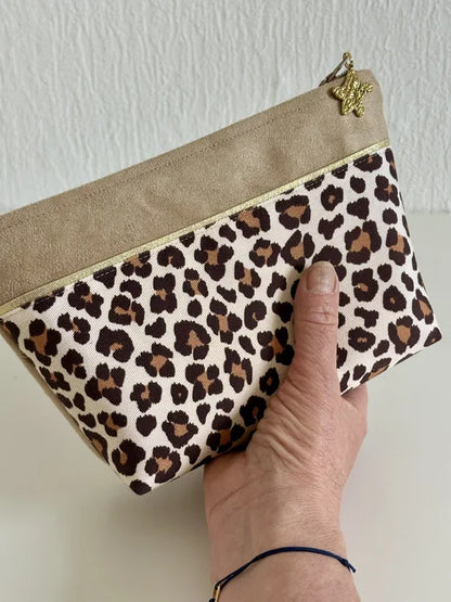 La trousse à maquillage léopard tenue en main.