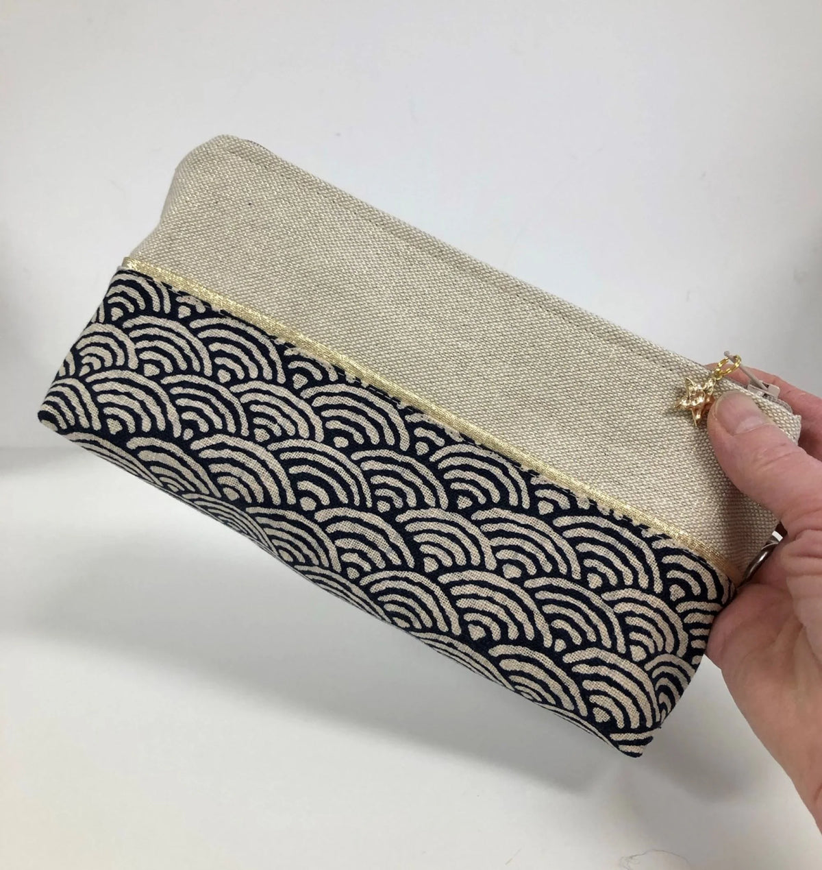 La trousse à stylos en tissu japonais bleu nuit et doré, tenue en main.