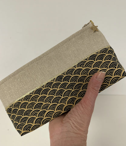 La trousse à stylos en tissu japonais Seigaiha bleu marine et doré, tenue dans la main.